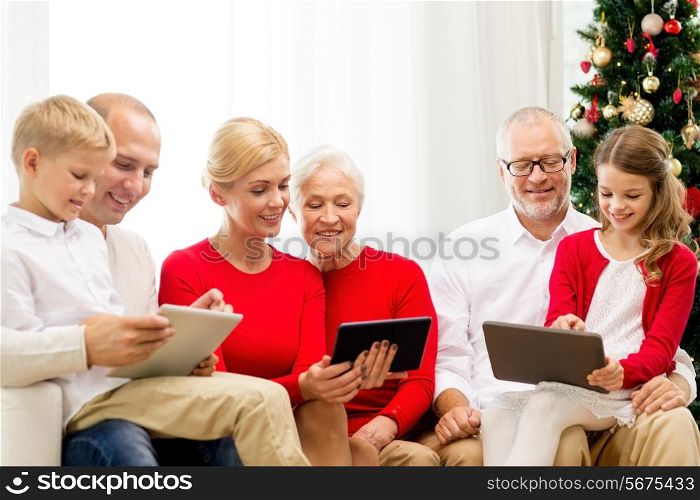 family, holidays, christmas, technology and people concept - smiling family with tablet pc computers sitting on couch at home