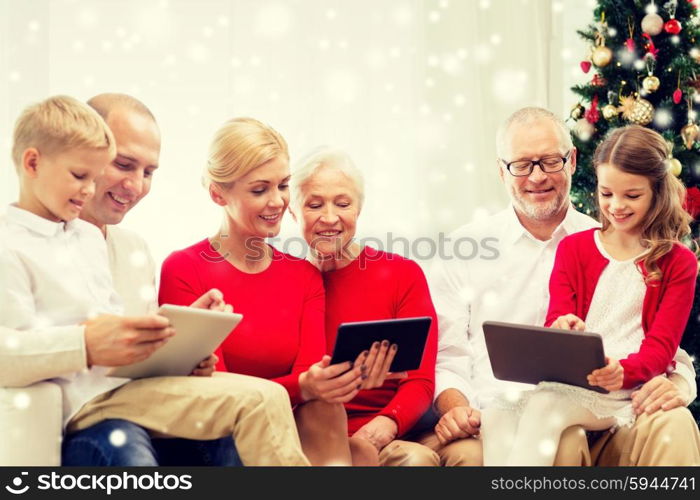 family, holidays, christmas, technology and people concept - smiling family with tablet pc computers sitting on couch at home