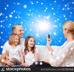 family, holidays, christmas technology and people - smiling mother, father and little girls with camera over blue snowy background