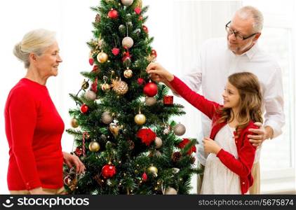 family, holidays, generation and people concept - smiling family decorating christmas tree at home