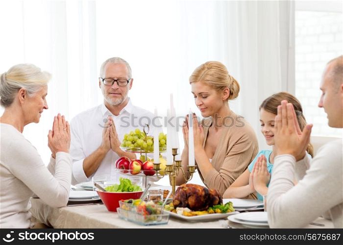family, holidays, generation and people concept - smiling family having dinner and praying at home