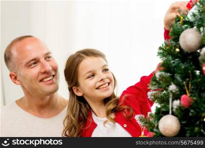 family, holidays, generation and people concept - smiling girl with father decorating christmas tree at home