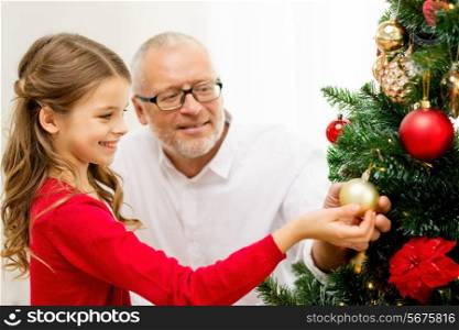 family, holidays, generation and people concept - smiling girl with grandfather decorating christmas tree at home
