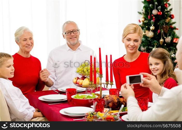 family, holidays, generation, christmas and people concept - smiling family having dinner and making photo with camera at home