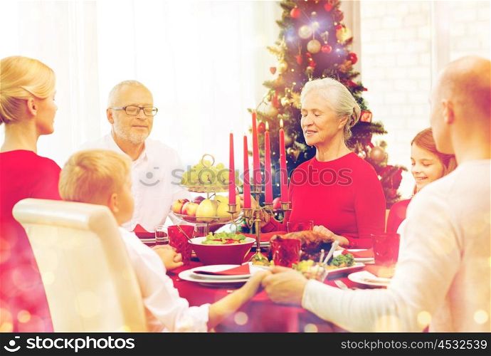 family, holidays, generation, christmas and people concept - smiling family having dinner and praying at home. smiling family having holiday dinner at home