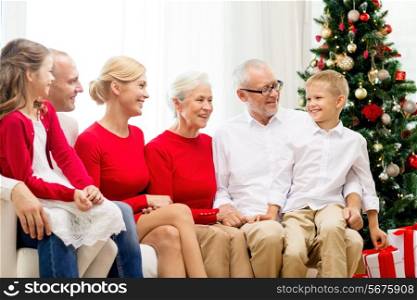 family, holidays, generation, christmas and people concept - smiling family sitting on couch at home