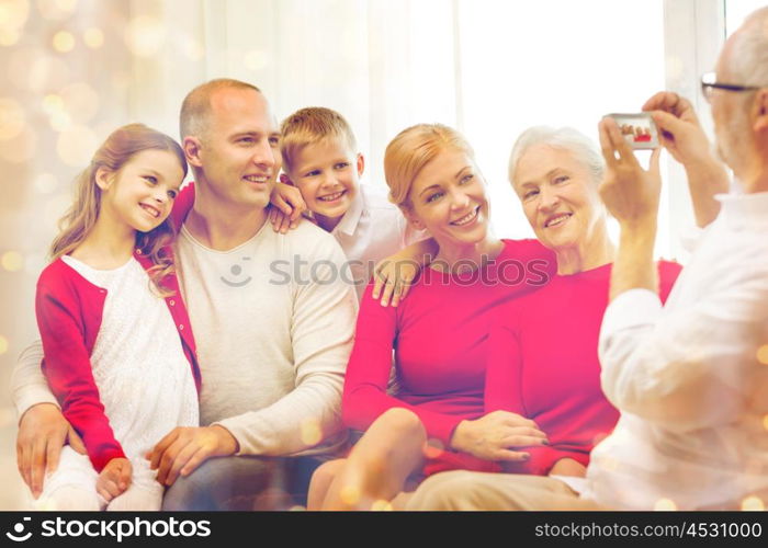 family, holidays, generation, christmas and people concept - smiling family with camera photographing and sitting on couch at home
