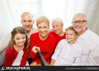 family, holidays, generation, christmas and people concept - smiling family with camera and selfie stick taking picture at home