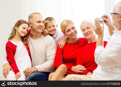 family, holidays, generation, christmas and people concept - smiling family with camera photographing and sitting on couch at home