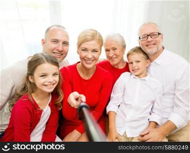 family, holidays, generation, christmas and people concept - smiling family with camera and selfie stick making picture at home