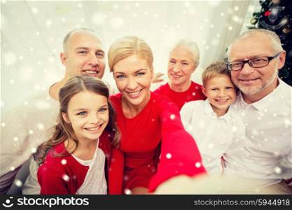 family, holidays, generation, christmas and people concept - smiling family with camera or smartphone taking selfie at home