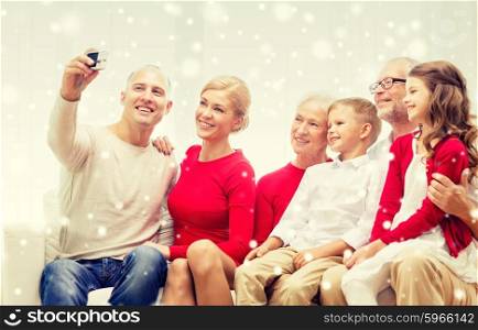 family, holidays, generation, christmas and people concept - smiling family with camera making selfie and sitting on couch at home
