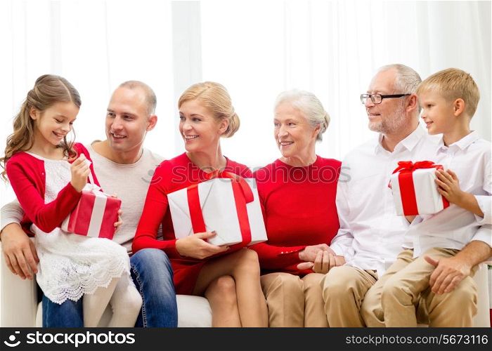 family, holidays, generation, christmas and people concept - smiling family with gift boxes sitting on couch at home