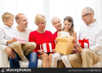 family, holidays, generation, christmas and people concept - smiling family with gift boxes sitting on couch at home