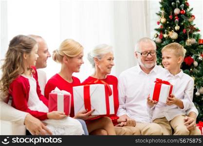 family, holidays, generation, christmas and people concept - smiling family with gift boxes sitting on couch at home