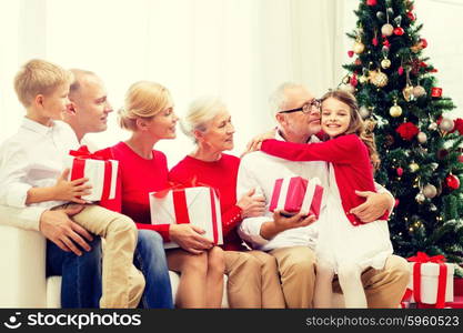 family, holidays, generation, christmas and people concept - smiling family with gift boxes sitting on couch at home