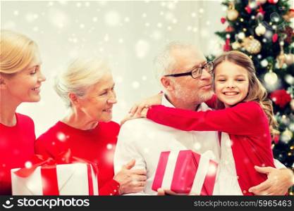 family, holidays, generation, christmas and people concept - smiling family with gift boxes hugging and kissing at home