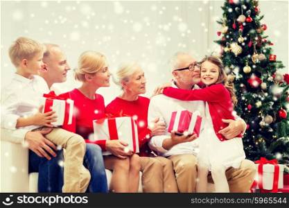 family, holidays, generation, christmas and people concept - smiling family with gift boxes sitting on couch and hugging at home