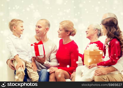 family, holidays, generation, christmas and people concept - smiling family with gift boxes sitting on couch and talking at home