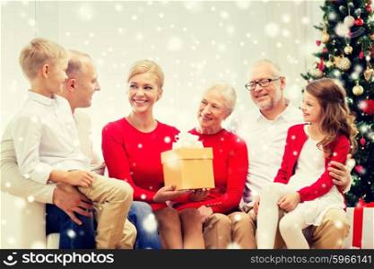 family, holidays, generation, christmas and people concept - smiling family with gift box sitting on couch at home