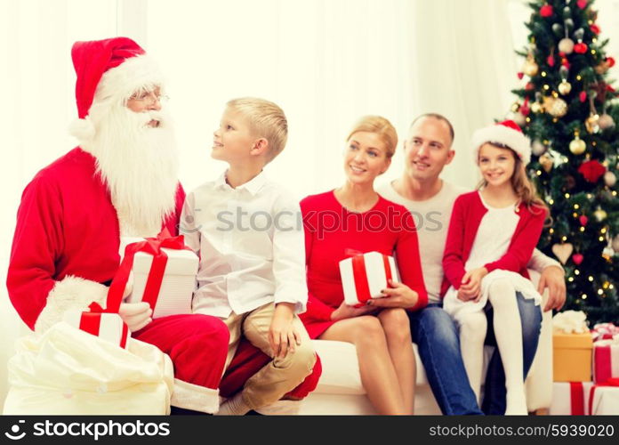 family, holidays, generation, christmas and people concept - smiling family with santa claus and gift boxes at home