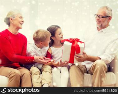 family, holidays, generation, christmas and people concept - smiling grandparents and grandchildren with gift box sitting on couch at home