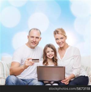 family, holidays, shopping, technology and people concept - happy family with laptop computer and credit card over blue lights background
