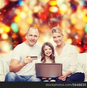 family, holidays, shopping, technology and people concept - happy family with laptop computer and credit card over red lights background