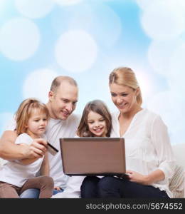 family, holidays, shopping, technology and people - happy family with laptop computer and credit card over blue lights background