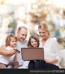 family, holidays, shopping, technology and people - happy family with laptop computer and credit card over lights background