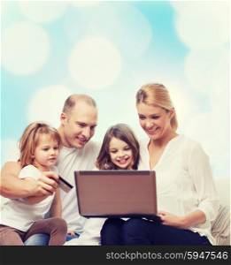 family, holidays, shopping, technology and people - happy family with laptop computer and credit card over blue lights background
