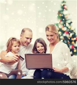 family, holidays, shopping, technology and people - happy family with laptop computer and credit card over living room and christmas tree and snow