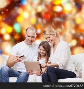 family, holidays, shopping, technology and people - smiling family with tablet pc computer and credit card over red lights background