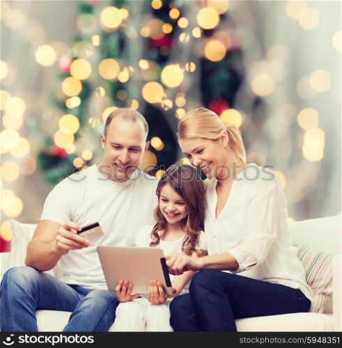 family, holidays, shopping, technology and people - smiling family with tablet pc computer and credit card over christmas tree lights background