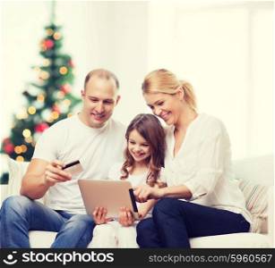 family, holidays, technology and people - smiling mother, father and little girl with tablet pc computers over living room and christmas tree background