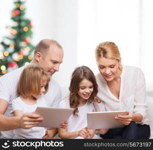 family, holidays, technology and people - smiling mother, father and little girls with tablet pc computers over living room and christmas tree background