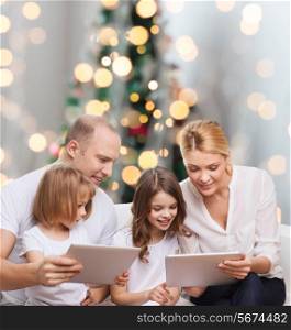 family, holidays, technology and people - smiling mother, father and little girls with tablet pc computers over christmas tree lights background