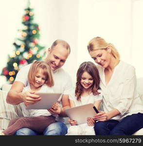 family, holidays, technology and people - smiling mother, father and little girls with tablet pc computers over living room and christmas tree background