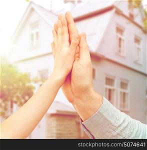 family, home and people concept - father and child holding hands together or making high five over house background. father and child hands making high five over house