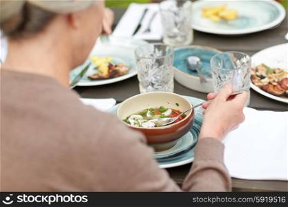 family, home, dinner, holidays and people concept - close up of woman eating soup in summer garden