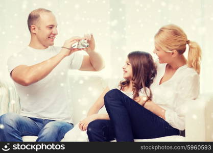 family, home, technology and people - happy family with camera taking picture over snowflakes background