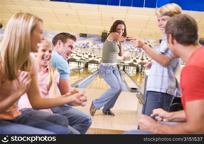 Family in bowling alley with two friends cheering and smiling