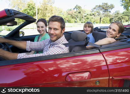 Family in convertible car smiling