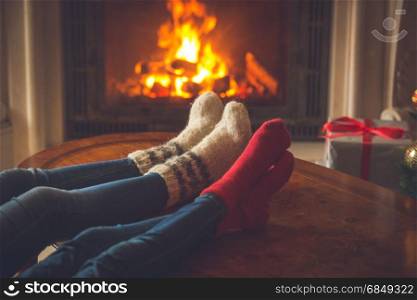 Family in cosy knitted socks warming at fireplace decorated for Christmas