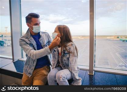 Family in face mask in airport. Father and child wear facemask during coronavirus and flu outbreak. Protection against Coronavirus and gripp. Dad and little girl with medical masks at airport. Protection against Coronavirus and gripp