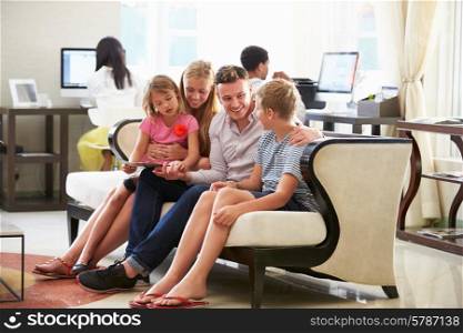 Family In Hotel Lobby Looking At Digital Tablet