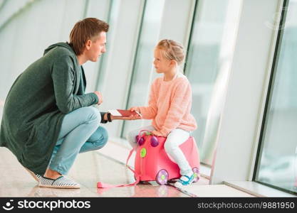 Family in international airport terminal waiting the flight. Happy dada and little girl with boarding pass at airport