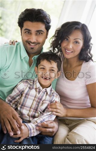 Family in living room sitting on sofa smiling (high key)