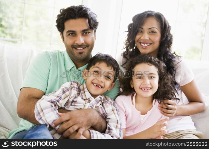 Family in living room sitting on sofa smiling (high key)