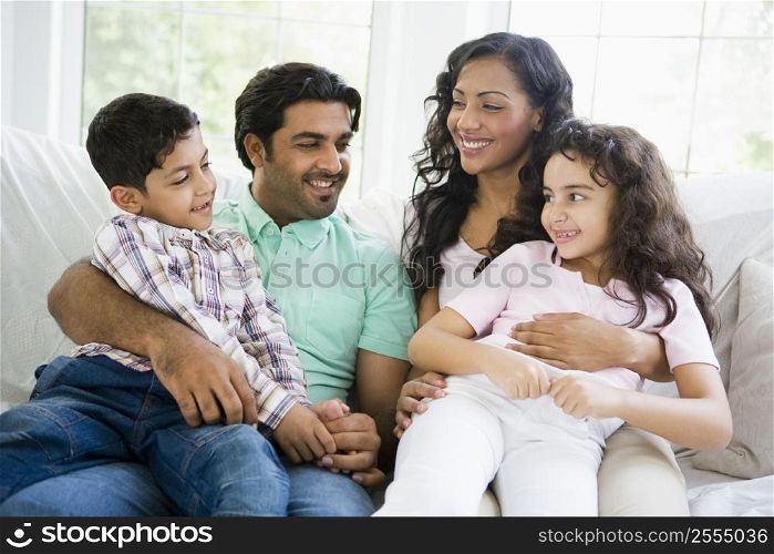 Family in living room sitting on sofa smiling (high key)